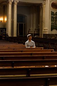 Full length of man sitting on seat in building