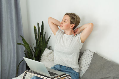 Young woman using laptop while sitting on sofa at home