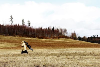 Woman running on field against sky