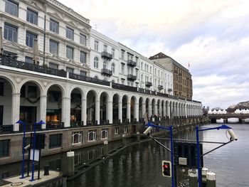 View of buildings by canal against sky in city