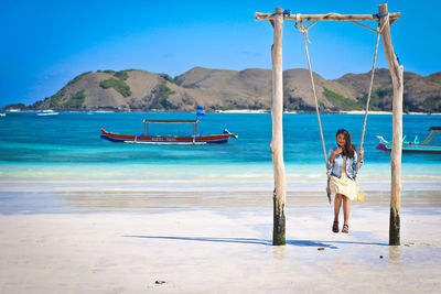 Rear view of woman on beach against sky