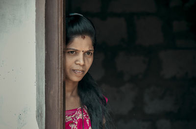 Portrait of smiling young woman standing against wall
