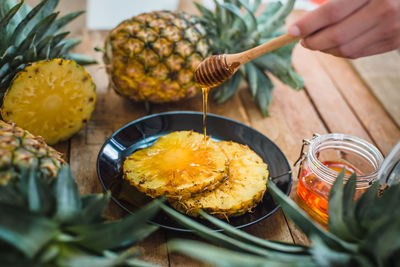Cropped hand pouring honey on pineapple slice
