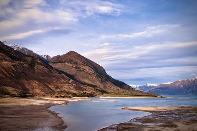 Scenic view of lake by mountains against sky