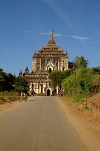 Empty road leading towards ancient temple against sky