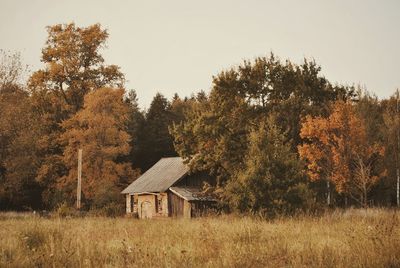 House on field by trees against sky