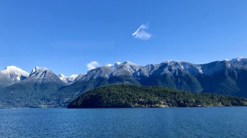 Scenic view of lake and mountains against blue sky