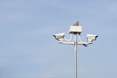 Low angle view of security cameras against sky