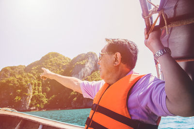 Portrait of young man standing in water against clear sky