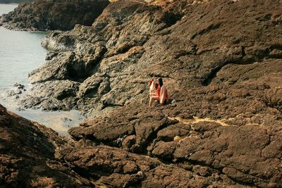 High angle view of woman on rock at beach during sunny day