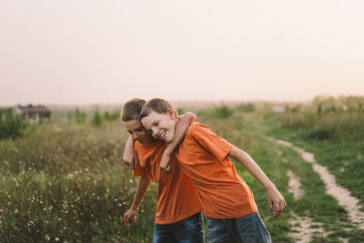 Funny twin brother boys playing outdoors on field at sunset.
