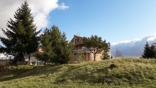 House on field by trees against sky