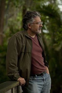 Thoughtful man wearing jacket looking away while standing in park