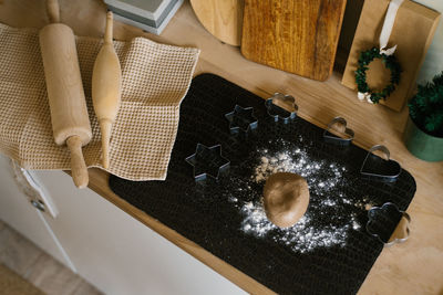 Gingerbread cookie dough is on the table and cutting molds, wooden rolling pins and a towel 