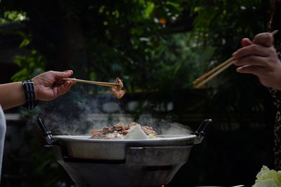 Close-up of person preparing food on barbecue grill