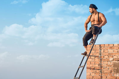 Low angle view of shirtless man against the sky