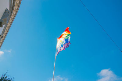 Low angle view of red flag against blue sky