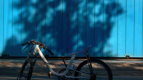 Bicycle parked on street against blue fence