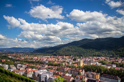 High angle view of residential district by mountain range against cloudy sky