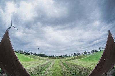 Scenic view of grassy field against cloudy sky