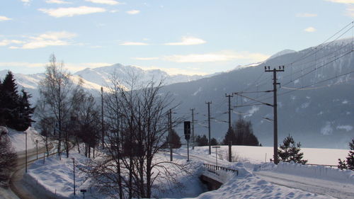 Snow covered trees and mountains against sky