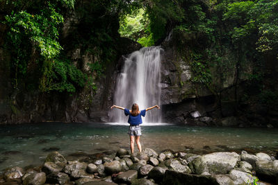 Woman looking at waterfall in forest