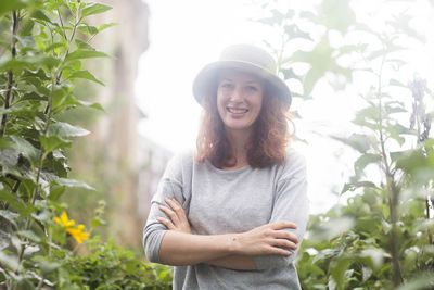 Young woman outside standing in an urban garden with a hat