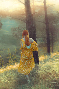 Rear view of woman walking on land in forest