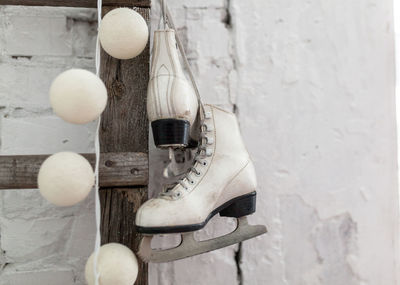 Close-up of ice skates hanging on ladder against wall