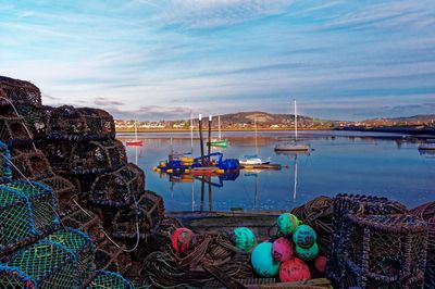 Fishing boats moored at harbor against sky