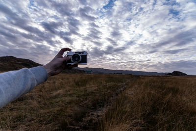 Man photographing camera on field against sky