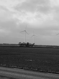 Windmills on field against sky