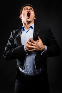 Opera singer singing while standing against black background