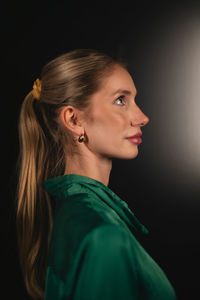 Side view of woman looking away against black background