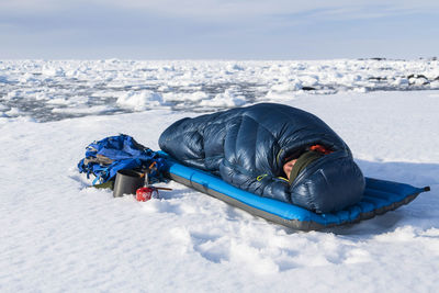 Male hiker relaxing in sleeping bag on snow covered mountain