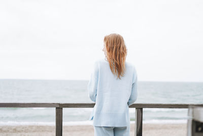 Rear view of woman standing against sea