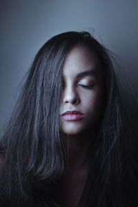 Close-up of young woman against gray wall