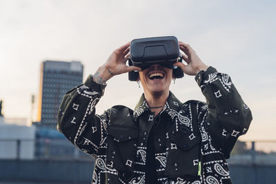 Happy man enjoying wearing virtual reality headset in city