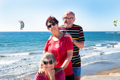 Portrait of friends enjoying at beach against sky