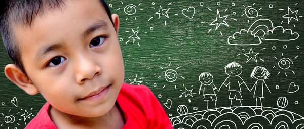 Portrait of boy against drawings on blackboard