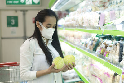 Close-up of woman wearing mask buying cabbages