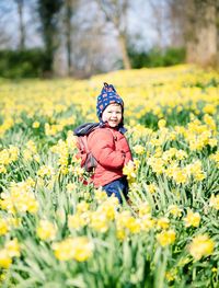 Rear view of girl with yellow flowers on field