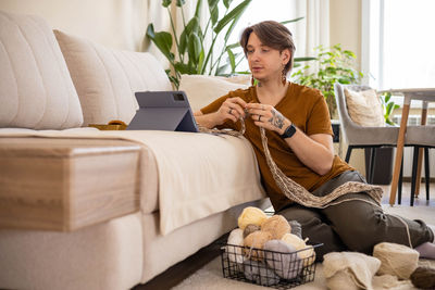 Young woman using mobile phone while sitting on sofa at home