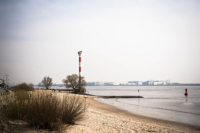 Lighthouse by sea against sky in city