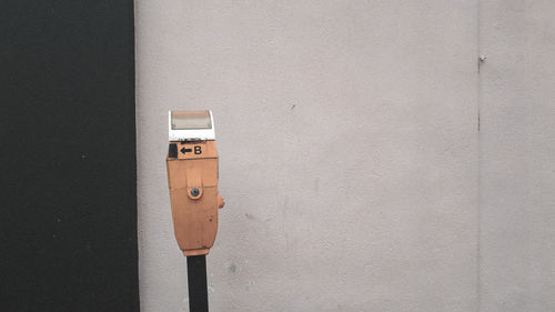 Close-up of parking meter against wall