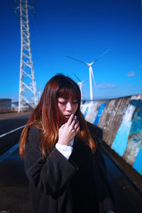 Beautiful young woman standing against sky