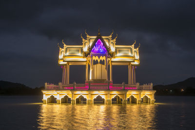 Illuminated building against cloudy sky