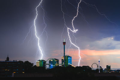 Lightning over illuminated city against sky at night