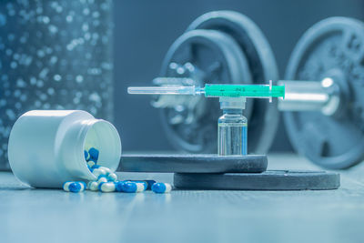 Dumbbells, syringe with needle, pills and vial with steroids. illegal doping in sport concept