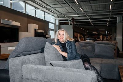 Beaming mature woman with radiant silver hair sitting comfortably on a dark sofa